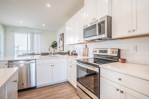 a modern kitchen with white cabinets and stainless steel appliances